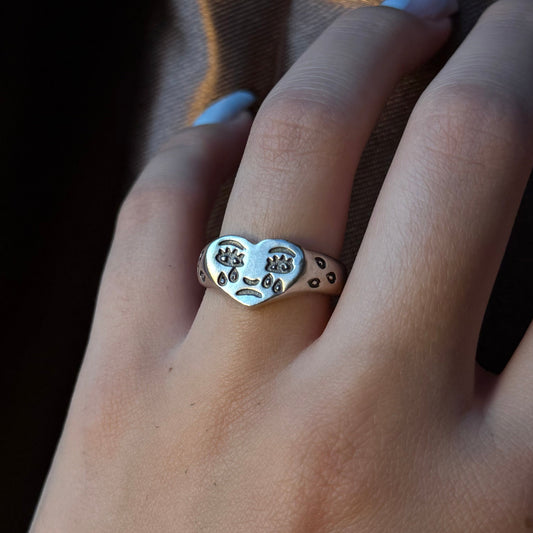 Adjustable silver ring with a heart design and engraved expressive face